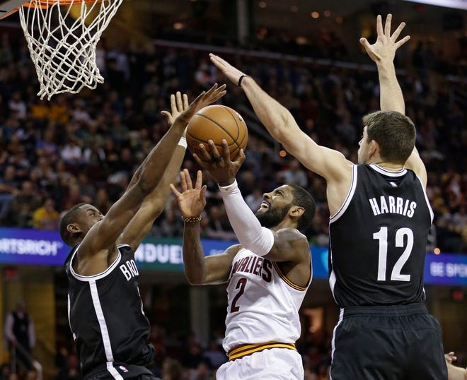 Cleveland Cavaliers' Kyrie Irving, center, drives against Brooklyn Nets' Caris LeVert, left, and Joe Harris in the second half of an NBA basketball game, Friday, Dec. 23, 2016, in Cleveland. (AP Photo/Tony Dejak)