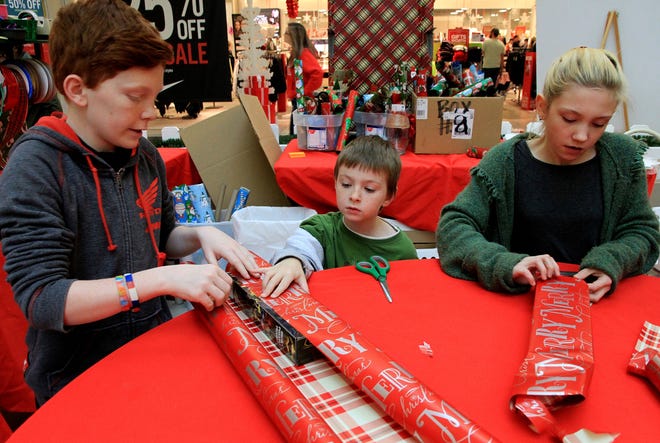 Joey Bistodeau, from left, Shaun Lee and Emma McAlister wrap Christmas gifts Friday, Dec. 23, 2016, at the Arkansas Valley Habitat for Humanity Gift Wrap Center in Central Mall. Located in front of J.C. Penney, the wrapping center will be open Dec. 24, 2016, during mall hours and will wrap gifts for $3-$12 with all proceed from the gift wrap center will be used locally to fund construction of simple, decent houses for local families in need. Joey is the 13-year-old son of Tandy McAlister, Shaun, 7, and Emma, 10, are the children of Tandy and Michael McAlister. JAMIE MITCHELL/TIMES RECORD
