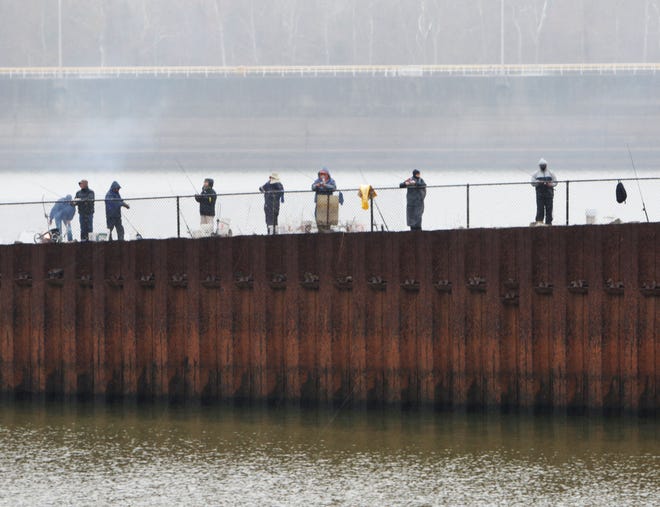 Fishermen brave the wet and cold weather Friday, Dec. 23, 2016, to try their luck at the catfish in the backwaters of the Clyde T. Ellis Hydroelectric Generation Station on the Arkansas River at the James W. Trimble Lock & Dam under the U.S. 59 Bridge. JAMIE MITCHELL/TIMES RECORD