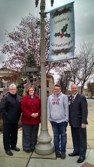 SUBMITTED PHOTO The New Philadelphia Business and Community Association partnered with Buckeye Career Center to design and produce the holiday banners for downtown New Philadelphia. Students in the Graphic Arts class submitted designs and the chosen entry was created by Malachai Reynolds. Reynolds' home school is Conotton Valley. Standing with the new holiday banner are: New Philadelphia Mayor, Joel B. Day (left); NPBCA Director, Julie Levengood Stephon; Reynolds and BCC Director of Curriculum, Instruction and Adult Education, Frank Polen.