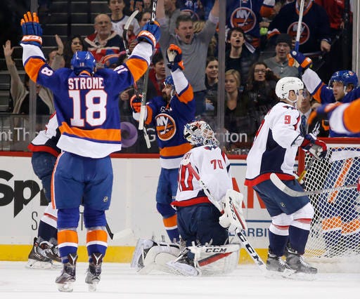 New York Islanders' Ryan Strome, (18), Cal Clutterbuck, center, and others celebrate after Clutterbuck scored a goal on Washington Capitals' goalie Braden Holtby (70) during the first period of an NHL hockey game, Tuesday, Dec. 27, 2016, in New York. (AP Photo/Kathy Willens)