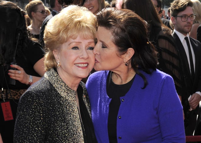In this Sept. 10, 2011, file photo, Debbie Reynolds, left, and Carrie Fisher arrive at the Primetime Creative Arts Emmy Awards in Los Angeles. Reynolds, star of the 1952 classic "Singin' in the Rain" died Wednesday, Dec. 28, 2016, according to her son Todd Fisher. She was 84. THE ASSOCIATED PRESS