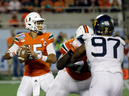 Miami quarterback Brad Kaaya, left, looks for a receiver as he is rushed by West Virginia defensive lineman Noble Nwachukwu (97) during the first half of the Russell Athletic Bowl NCAA college football game, Wednesday, Dec. 28, 2016, in Orlando, Fla. (AP Photo/John Raoux)