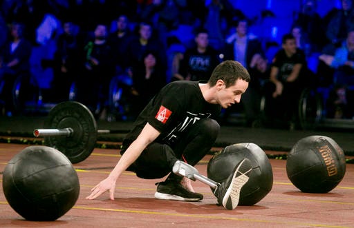 In this photo taken Saturday Dec. 24, 2016, Ukraine's army captain Serhiy Romanovsky, 26, with his right leg prosthesis, takes part in the CrossFit competition for disabled servicemen at the Sport Arena in Kiev, Ukraine. About 50 wounded soldiers and veterans participated in Ukraine’s Game of Heroes, which included weightlifting, rope climbing and rowing machines. (AP Photo/Efrem Lukatsky)