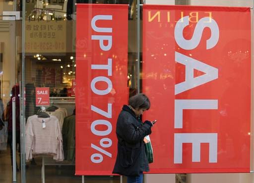 In this Wednesday, Dec. 28, 2016 photo, a woman uses her smartphone in front of sale signs at a shopping district in Seoul, South Korea. South Korea's finance ministry said Thursday, Dec. 29, 2016, that Asia's fourth-largest economy will likely expand 2.6 percent next year, the same pace as its outlook for 2016, down from its earlier forecast of 3.0 percent. (AP Photo/Ahn Young-joon)