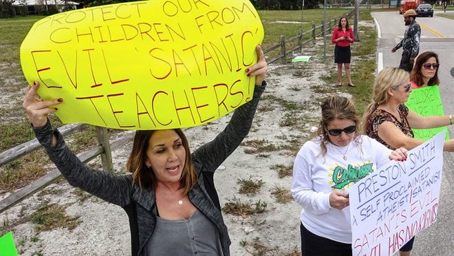 Lauren Kalina (left), mother of a 7th grade student at Boca Raton Middle School, protests against teacher Preston Smith along with other parents in front of the school December 21. Smith is responsible for the pentagram display at Boca Raton’s Sanborn Square. (Lannis Waters / The Palm Beach Post)