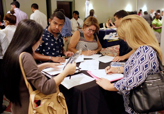 FILE - In this July 19, 2016, file photo, people fill out job applications at a job fair in Miami Lakes, Fla. On Thursday, Dec. 29, 2016, the Labor Department reported that fewer Americans applied for unemployment benefits the week before. (AP Photo/Lynne Sladky, File)