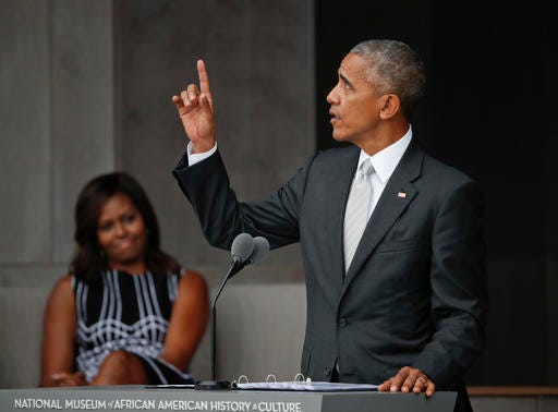 FILE - In this Saturday, Sept. 24, 2016 file photo, President Barack Obama points upward during the dedication ceremony for the Smithsonian Museum of African American History and Culture on the National Mall in Washington. “It is a monument, no less than the others on this Mall, to the deep and abiding love for this country, and the ideals upon which it is founded. For we, too, are America," he said. At left is first lady Michelle Obama. (AP Photo/Pablo Martinez Monsivais)