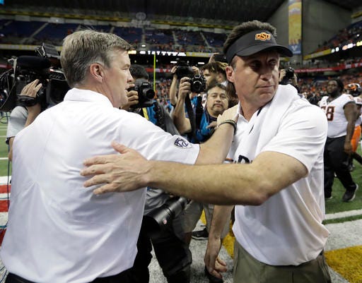 Colorado coach Mike MacIntyre, left, and Oklahoma State coach Mike Gundy, right, meet at midfield following the Alamo Bowl NCAA college football game, Thursday, Dec. 29, 2016, in San Antonio. Oklahoma State won 38-8. (AP Photo/Eric Gay)