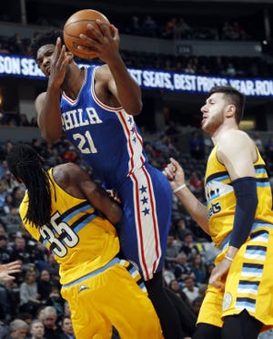 The Sixers' Joel Embiid is called for an offensive foul as he drives to the basket between Nuggets forward Kenneth Faried (left) and center Jusuf Nurkic in the first half  Friday, Dec. 30, 2016, in Denver.