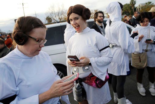 Members of the Krewe of Chewbacchus, a Mardi Gras Krewe, dressed as Princess Leia, use their smart phones at the start of a parade in honor of actress Carrie Fisher, who played Leia in the "Star Wars" movie series, in New Orleans, Friday, Dec. 30, 2016. Fisher died on Dec. 27, 2016, at the age of 60. (AP Photo/Gerald Herbert)