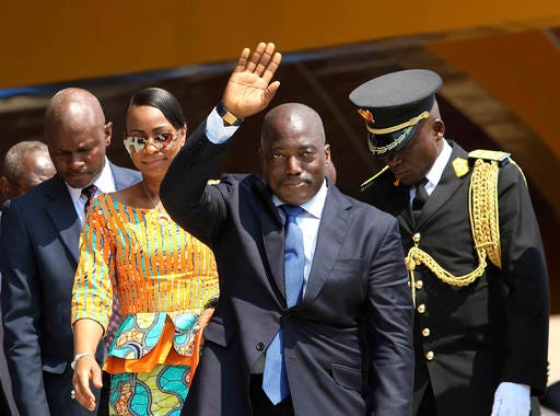 FILE- In this Thursday, June 30, 2016 file photo, Congolese President Joseph Kabila, center, waves as he and others celebrate independence for the Democratic Republic of Congo in Kindu, Congo. On Saturday, Dec. 31, 2016, political parties signed a deal that calls for Kabila to leave power after an election that now will be held by the end of next year instead of mid-2018 as his party originally proposed. (AP Photo/John Bompengo, File)
