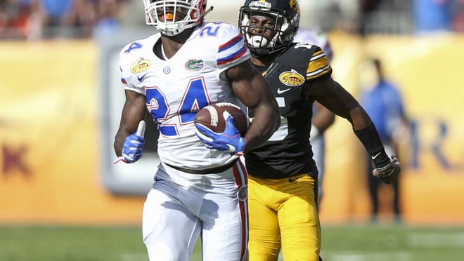 Florida running back Mark Thompson (24) runs past Iowa defensive back Joshua Jackson (15) on his way to a touchdown during the Gators’ 30-3 rout Monday of the Hawkeyes in the Outback Bowl in Tampa. (Andres Leiva/Tampa Bay Times/TNS)