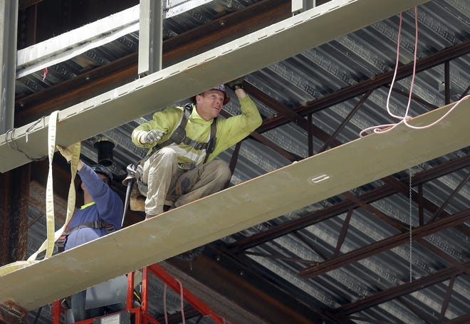 Workers construct a high-rise building in Boston. Business economists still expect U.S. economic growth to pick up in 2017, but they see a slowdown in hiring. The Associated Press