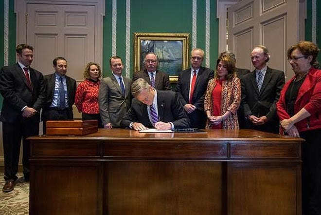 Gov. Baker signs the legislation, with Lt. Gov. Karyn Polito and Worcester Mayor Joseph Petty among those looking on. Submitted photo
