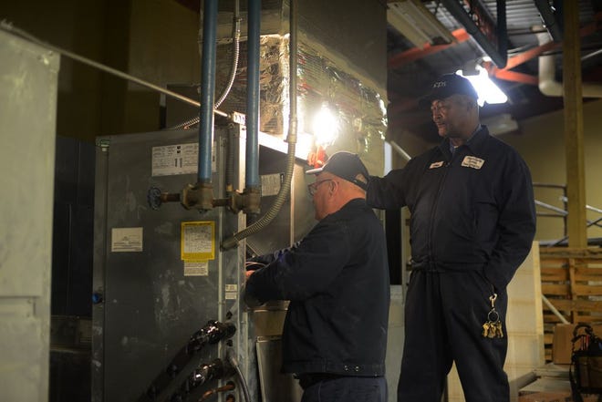From left, Ronnie Jones and Leon Edwards, Lenoir County Public Schools plant operators, work on a heating and air unit Friday inside the cafeteria at Kinston High School. The school system approved wage increases for maintenance workers.