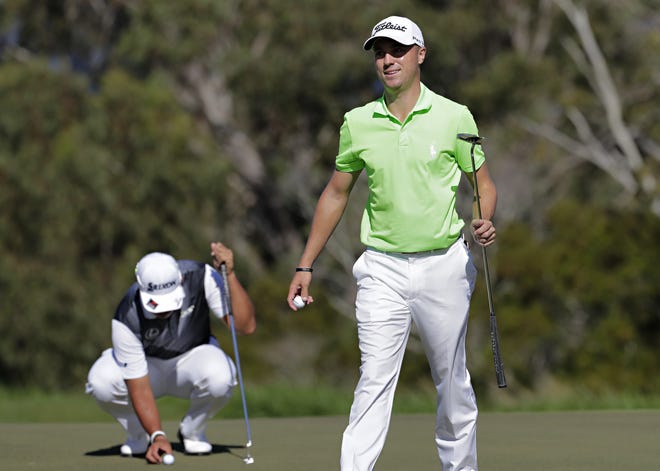 Justin Thomas, right, smiles after saving par on the fourth green as Hideki Matsuyama, of Japan, places his ball on the green during the final round of the Tournament of Champions Sunday at Kapalua Plantation Course in Kapalua, Hawaii. (AP Photo/Matt York)