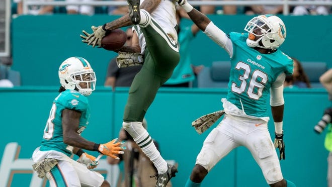 New York Jets wide receiver Robby Anderson (11) catches a pass between Miami Dolphins cornerback Bobby McCain (28) and Miami Dolphins cornerback Tony Lippett (36) at Hard Rock Stadium in Miami Gardens, Florida on November 6, 2016. (Allen Eyestone / The Palm Beach Post)