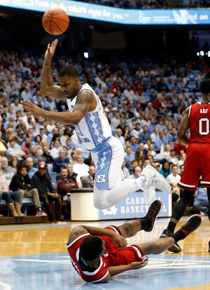 North Carolina's Seventh Woods is fouled by N.C. State's Markell Johnson, bottom, during Sunday's game.