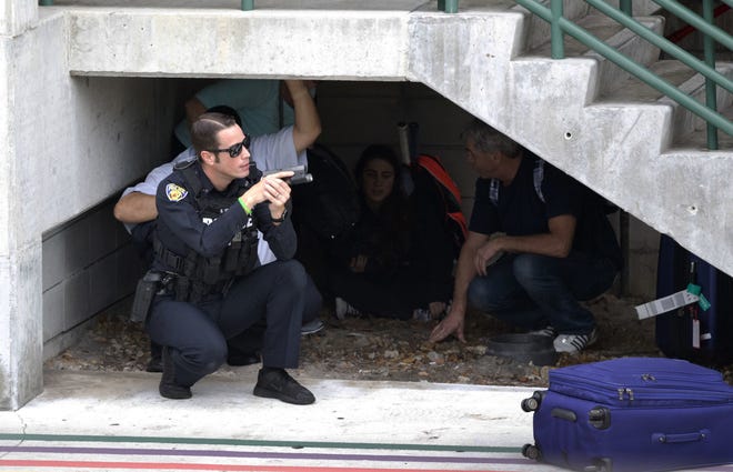 Law enforcement personnel shield civilians outside a garage area at Fort Lauderdale's Hollywood International Airport Friday after a gunman opened fire in the baggage claim area, killing five people. State Sen. Greg Steube has filed legislation to allow guns in airport terminals. THE ASSOCIATED PRESS / WILFREDO LEE