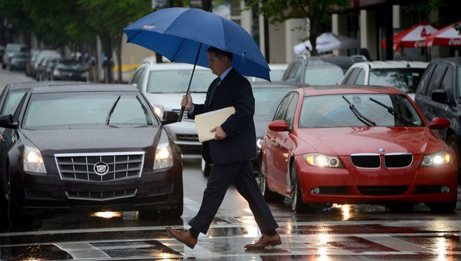 A pedestrian crosses Adams Street in front of the Duval County Courthouse protected by an umbrella as a steady rain falls around the area on April 14, 2016. (Bob Mack/Florida Times-Union)