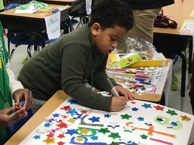 First-grader Stanley Davis colors in a spirit poster that his class was making with college students from York College on  Tuesday, Jan. 10, 2017,  as part of the Mount Holly School District's new "Kindergarten to College" program.