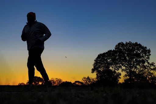 FILE - In this Tuesday, Nov. 22, 2016 file photo, a runner is silhouetted against the sunrise on his early morning workout near Arlington National Cemetery in Arlington, Va., across the Potomac River from the nation's capital. Research released on Monday, Jan. 9, 2017 suggests that people who pack their workouts into one or two days a week lower their risk of dying as much as those who exercise more often, as long as they get enough of it. (AP Photo/J. David Ake)