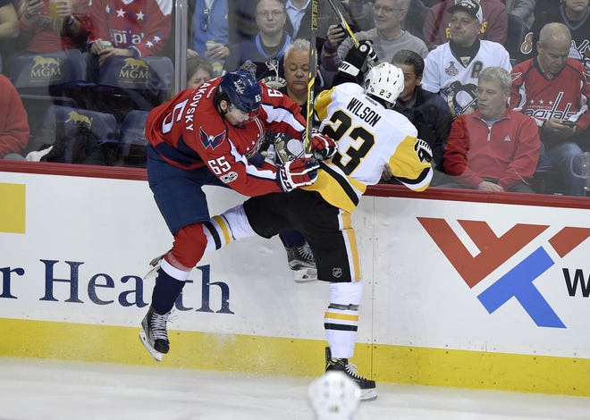 Capitals left wing Andre Burakovsky (65) checks Penguins left wing Scott Wilson (23) into the boards during the first period of Wednesday's game.