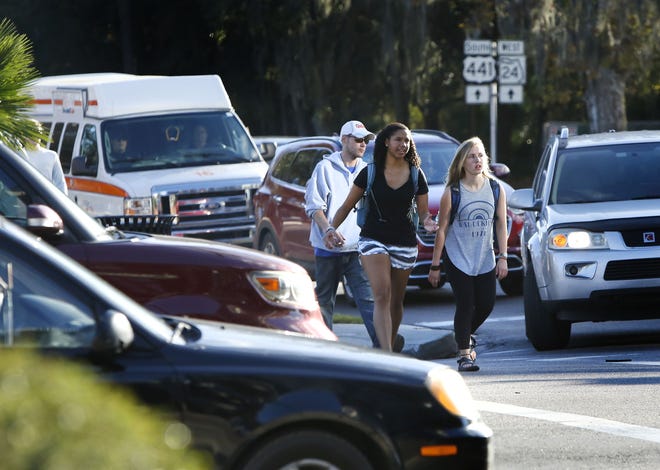 Pedestrians cross at the corner of University Avenue and 13th Street on Thursday in Gainesville. In the years 2005-14, an average of four pedestrians per year died in traffic accidents in the Gainesville metro area. (Brad McClenny/Staff photographer)