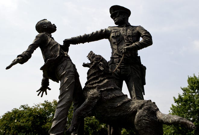 A young protester confronted by a police officer and a snarling police dog is depicted in a sculpture in Kelly Ingram Park in Birmingham. (AP Photo/Butch Dill)