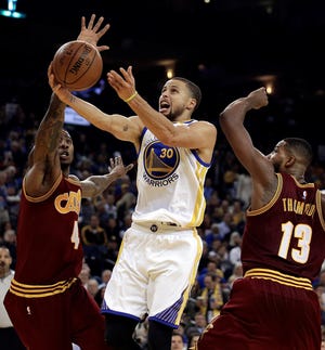 Golden State’s  Stephen Curry glides in for a basketball against Cleveland’s Iman Shumpert, left, and Tristan Thompson (13) Monday night in Oakland, Calif. BEN MARGOT/AP PHOTO
