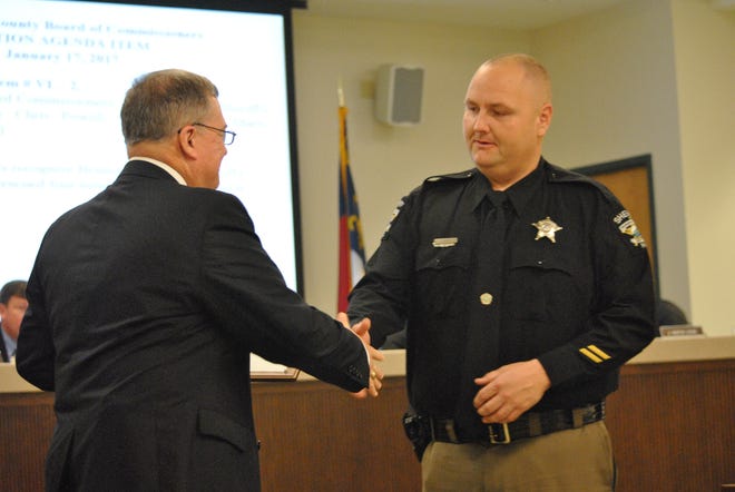 Commissioner Marty Cooke (left) shakes hands with Brunswick County Sheriff's Deputy Chris Powell, who was honored for saving four teenagers from a car accident last year. MAKENZIE HOLLAND/STARNEWS