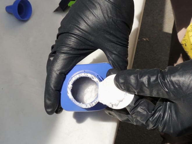 A member of the Royal Canadian Mounted Police opens a printer ink bottle containing the opioid carfentanil in Vancouver. Drug dealers have been cutting carfentanil and its weaker cousin, fentanyl, into heroin and other illicit drugs to boost profit margins.