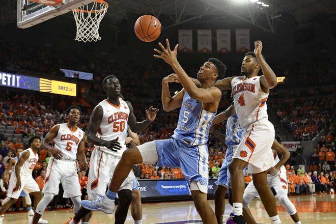 North Carolina's Tony Bradley reaches for a loose ball while defended by Clemson's Shelton Mitchell (4) and Sidy Djitte during the first half of an NCAA college basketball game, Tuesday, Jan. 3, 2017 in Clemson, S.C. (AP Photo/Richard Shiro)