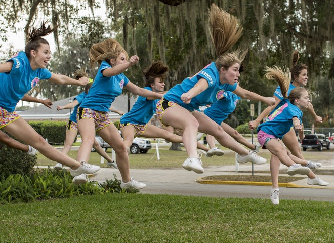 Varsity cheerleaders leap into the air as part of their routine at First Academy of Leesburg on Thursday. The squad recently won the Fellowship of Christian Cheerleaders national championship in Orlando. (Paul Ryan / Correspondent)