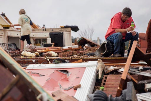Jeff Bullard sits in what used to be the foyer of his home as his daughter, Jenny Bullard, looks through debris at their home that was damaged by a tornado, Sunday, Jan. 22, 2017, in Adel, Ga. Gov. Nathan Deal declared a state of emergency in several counties, including Cook, that have suffered deaths, injuries and severe damage from weekend storms. (AP Photo/Branden Camp)