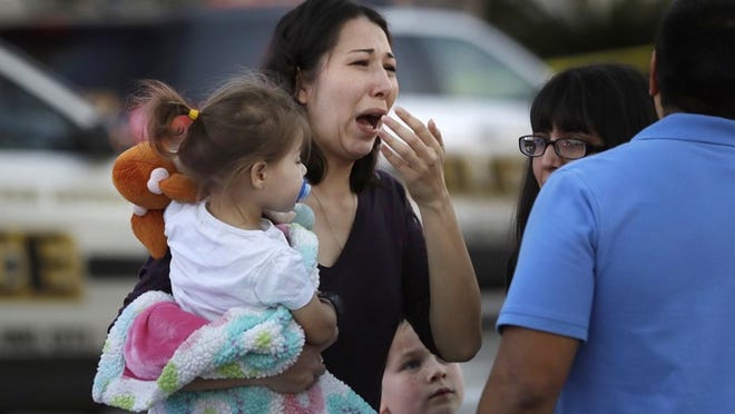 A woman holds her child after San Antonio police helped her and other shoppers exit the Rolling Oaks Mall on Sunday. Authorities said one man was killed and several people were hurt after a robbery at the shopping mall. (AP Photo/Eric Gay)