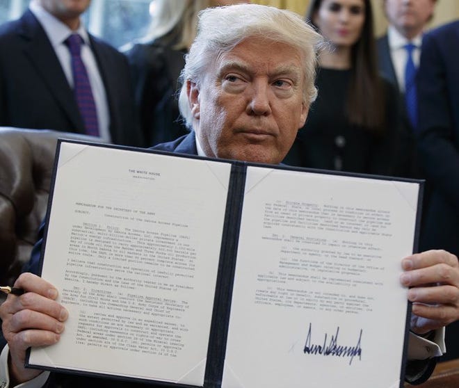 President Donald Trump shows off his signature on an executive order about the Dakota Access pipeline, Tuesday, Jan. 24, 2017, in the Oval Office of the White House in Washington. (AP Photo/Evan Vucci)