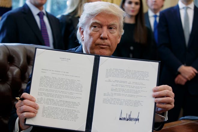 President Donald Trump shows off his signature on an executive order about the Dakota Access pipeline Tuesday in the Oval Office of the White House in Washington.