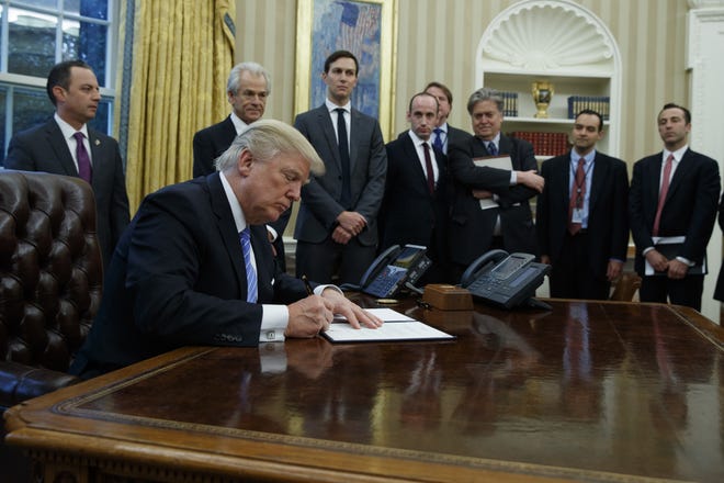 President Donald Trump signs an executive order implementing a federal government hiring freeze Monday in the Oval Office of the White House in Washington. EVAN VUCCI/THE ASSOCIATED PRESS