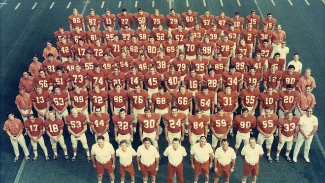 Handout photo of the University of Texas football team, circa 1969. Back, row 7, left to right: (#82) Tommy Woodard, (87) Jerrell Bolton, (11) Wayne Kirk, (77) Bill Atessis, (50) Bobby Wuensch, (75) Charles Crawford, (79) Tommy Matula, (60) “Syd” Sydney J. Keasler III, (57) Jim Achilles, (47) Paul Robichau, (10) Robbie Patman, (15) Bill Catlett, (15) Allshouse. Row 6, left to right: (26) Johnny Robinson, (61) Scott Henderson, (81) Hutson, (25) Donny Windham, (27) Tommy Asaff, (58) Buddy Hudgins, (52) Forrest Wiegand, (67) Glen Halsell, (43) Larry Webb, (39) Sam Lawless, (53) George McIngvale, (2) Jack Rushing, (36) David Ballew, Mgr. Kay. Row 5, left to right: Mgr. Fox, (42) Mack McKinney, (17) Gary Rike, (72) Jim Williamson, (71) Leo Brooks, (62) Bob McKay, (80) Bill Zapalac, (65) Scott Palmer, (70) Carl White, (88) Charles Speyrer, (78) Tommy Lee, (37) Rob Layne, (23) Danny Lester, Trainer Pippin. Row 4, left to right: Mgr. Cave, (81) — Anders, (48) Rick Troberman, (55) Braband, (49) Bob Huffman, (54) Rick Martin, (46) Bobby Callison, (38) Jimmy Hull, (79) Pat Macha, (35) Jim Bertelsen, (85) Stan Mauldin, (29) Robert Paine, (41) Rick Nabors, (5) Happy Feller, Trainer Baldwin. Row 3, left to right: Mgr. Cook, (56) Mike Speer, (51) Jeff Zapalac, (73) Travis Roach, (74) Randy Stout, (21) Dickie Johnston, (14) Eddie Phillips, (45) Ken Ehrig, (40) Randy Peschel, (16) James Street, (28) Fred Steinmark, (34) David Richardson, (19) Paul Kristynik, (12) Dan Terwalp, (90) Adger, Mgr. Simpson. Row 2, left to right: Mgr. Hobbs, (13) Jimmy Gunn, (63) George Cobb, (89) David Arledge, (32) Mike Hutchings, (86) Mike Campbell, (76) Chris Young, (68) Jay Cormier, (66) Mike Dean, (64) Bobby Mitchell, (31) Greg Ploetz, (55) Ronnie Tyler, (10) David Keeton, (20) Scotter Monzingo, Mgr. Hall. Row 1, left to right: Mgr. Lemmon, (17) D. Campbell, (18) Donnie Wigginton, (53) Rob Schultz, (44) Raymond Fontenot, (22) Billy Dale, (30) Steve Worster, (24) Ted Koy, (84) Tom Campbell, (59)