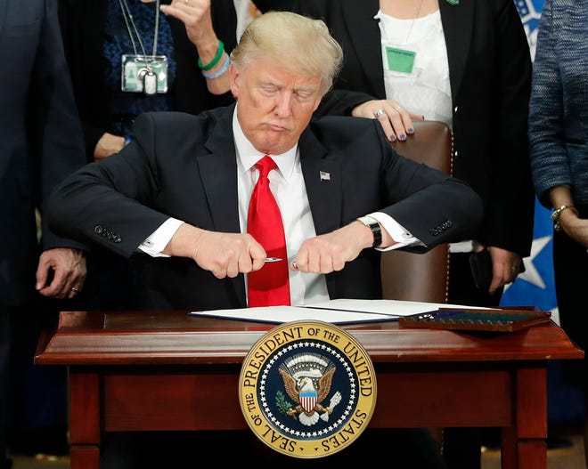 President Donald Trump takes the cap off a pen before signing executive order for immigration actions to build border wall during a visit to the Homeland Security Department in Washington, Wednesday, Jan. 25, 2017. (AP Photo/Pablo Martinez Monsivais)