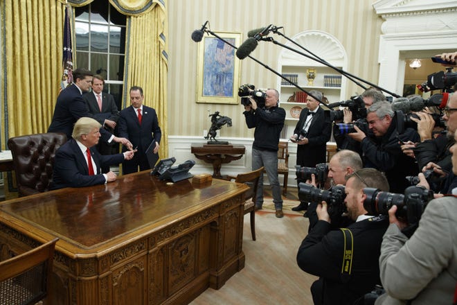 In this Jan. 20, 2017, photo, President Donald Trump hands over his pen after signing his first executive order in the Oval Office of the White House in Washington. It's the first full work week for the Trump administration, and the talk is all about emoluments, executive orders, a border tax, TPP and much more. (AP Photo/Evan Vucci)