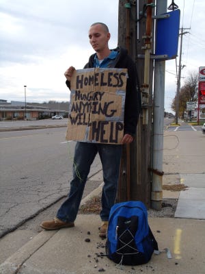 Daniel Brummelt panhandles along Eighth Street in a 2013 photo. According to Lyn Raymond at the Lakeshore Housing Alliance, the homeless population is falling as more people are finding jobs, but affordable housing is still an issue. File photo