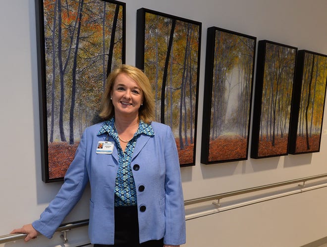 Pardee Hospital Chief Administrative Officer Johnna Reed with Stephen St. Claire's multi-panel painting "Walk in the Woods," displayed in a hall at the Pardee Cancer Center. Pardee purchased the work of 10 local and regional artists to adorn the walls of the new facility.
