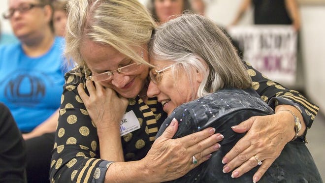 Overcome with emotion after speaking at an August state hearing on a fetal burial rule, Dr. Leslie Spotz, right, hugs Rose Ireland, a retired nurse.