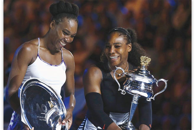 Serena Williams, right, holds the trophy after winning the 2017 Australian Open women's singles final against her sister Venus, left, on Saturday.