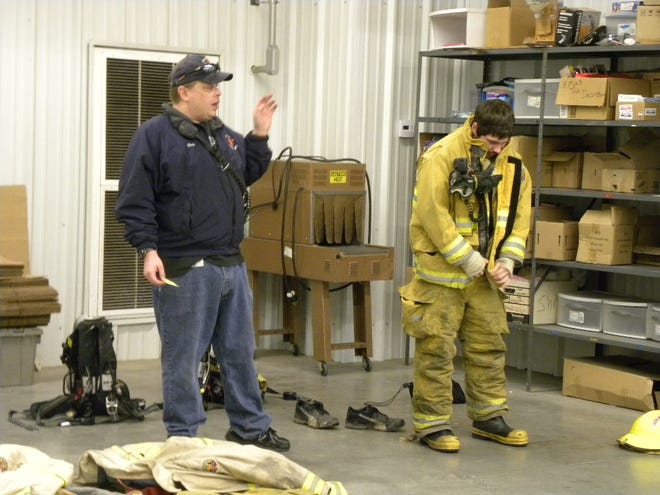 Chris Casella, left talks to people in the Arc of Steuben’s Vocational program about the equipment used by firefighters while Justin Smith demonstrates. Provided/The Leader