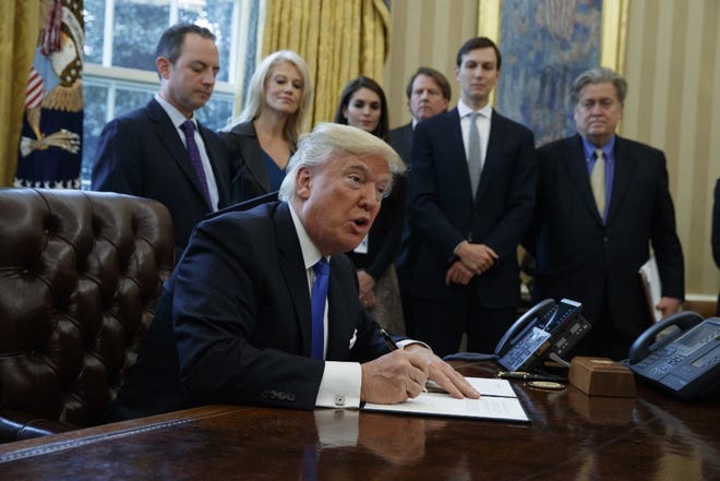 President Donald Trump signs an executive order on the Keystone XL pipeline, Tuesday, Jan. 24, 2017, in the Oval Office of the White House in Washington.