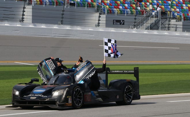 The No. 10 Konica Minolta Cadillac DPi-V.R waves the checkered flag as they head to victory lane after winning the 55th running of the Rolex 24 on Sunday. NEWS-JOURNAL/JIM TILLER